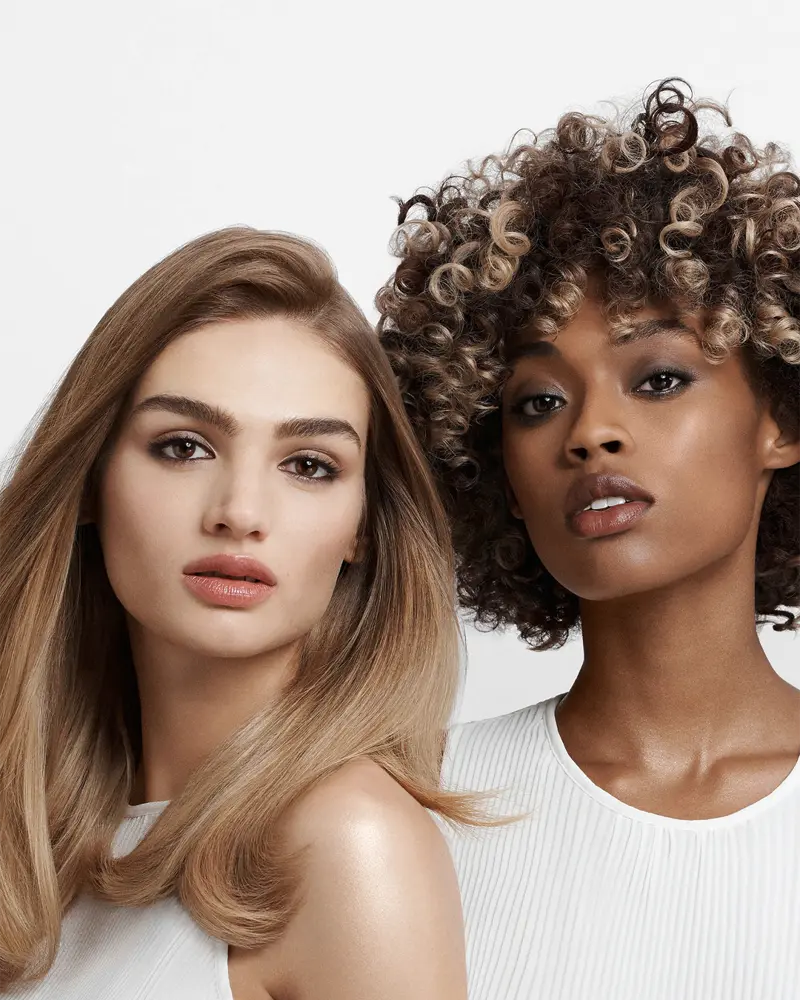 Two friends laughing and enjoying manicures together during a refer-a-friend salon visit.